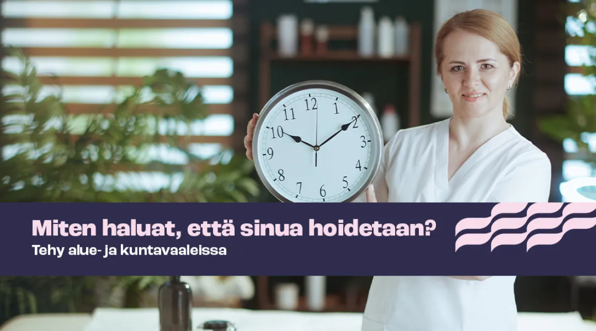 Kuvassa hoitaja katsoo kameraan ja pitää käsissään seinäkelloa.