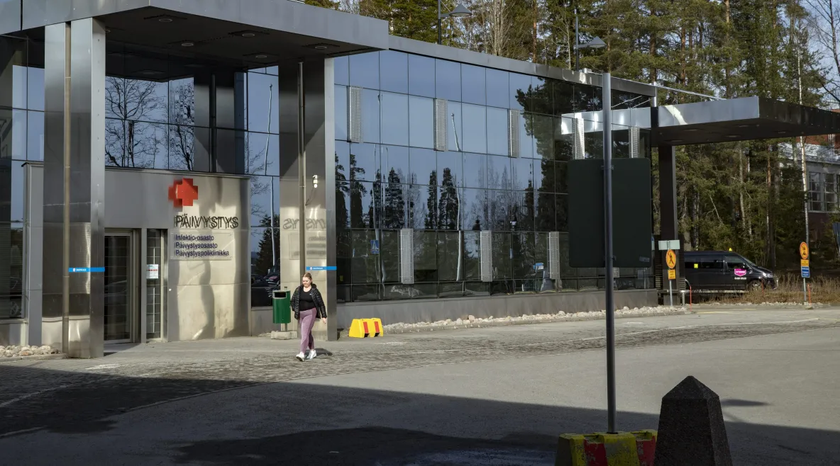 Sairaalan pihalla kävelee ihminen.