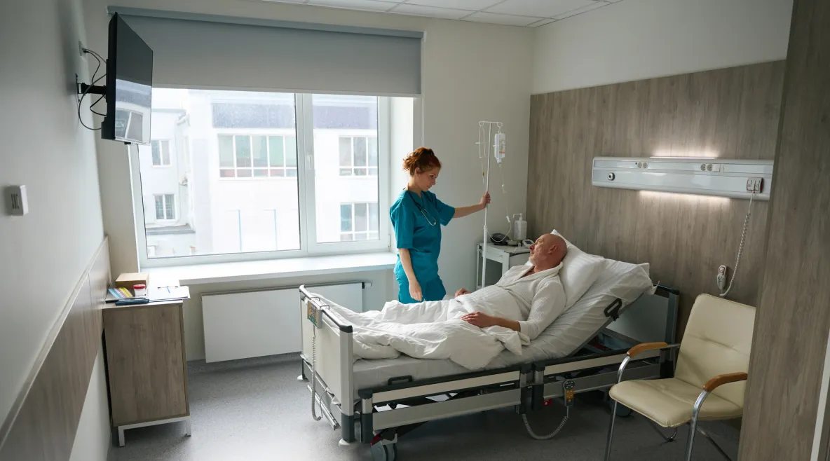 Potilas makaa sängyssä ja sairaanhoitaja on vierellä.
