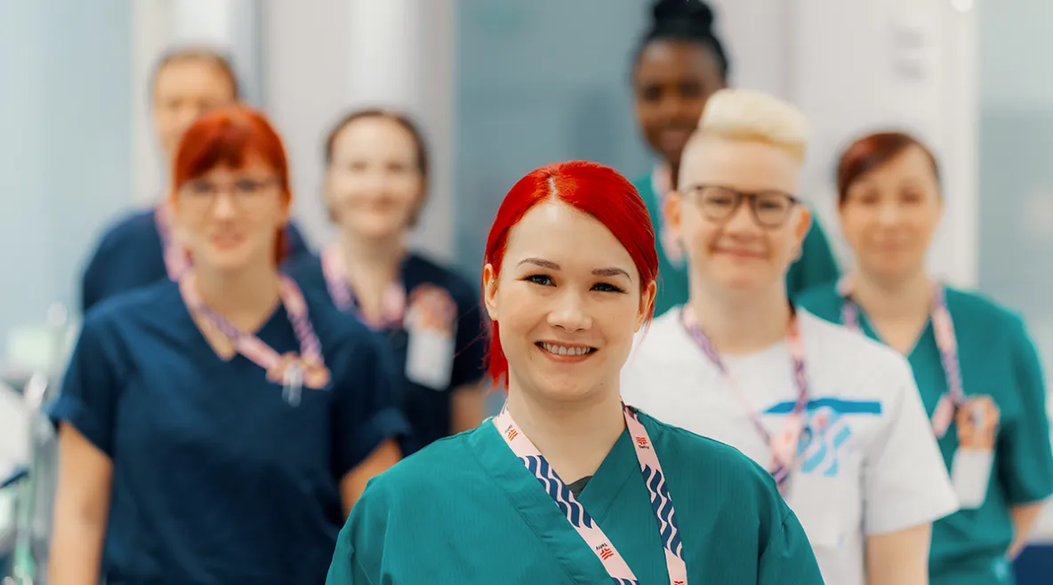 Kuvassa hoitajia, jotka hymyilevät. Hoitajilla on kaulassa Tehyn kaulanauha.