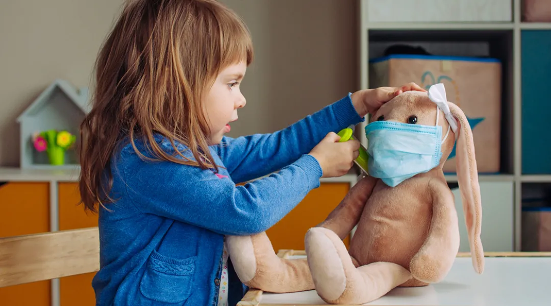 Pikkutyttö leikkii lääkäriä ja antaa rokotteen pehmolelu jänikselle.