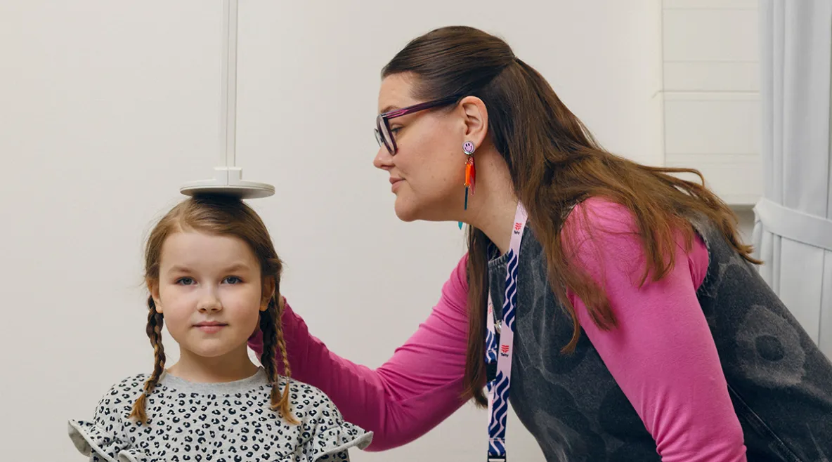 Terveydenhoitaja mittaa lapsen pituutta