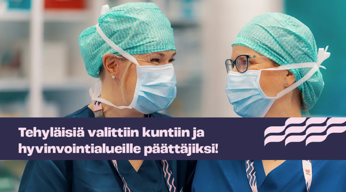 Kaksi sairaanhoitajaa maskit yllään katsoo hymyillen toisiinsa. 