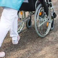 Hoitaja työntää pyörätuolia