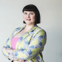 Nainen jakkupuvussa hymyilee.