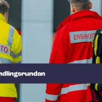 Kuvassa kaksi ensihoitajaa, joista toinen kantaa reppua. Kuvassa teksti "förhandlingsrundan".