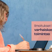 Nainen kynä kädessä tietokoneen äärellä.