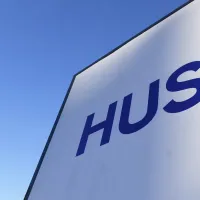 Kuvassa näkyy vaaleansinistä taivasta ja seinä, jossa on logo HUS.
