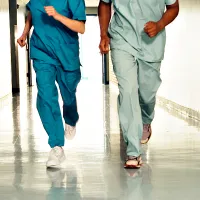 Kaksi hoitajaa juoksee sairaalan käytävällä.