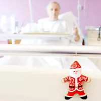 Kuvassa on taustalla ikääntynyt miespotilas sairaalavuoteessa ja etualalla vuoteen päädyssä roikkuu joulutontun muotoinen joulukoriste.