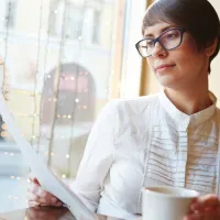 Nuori nainen lukee sopimusta kahvilassa_istock