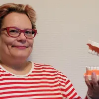 Nainen pitää hammashallia kädessään.