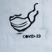 Graffiti, jossa maski ja teksti Covid-19.