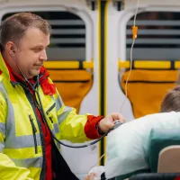 Kaksi ensihoitajaa hoitaa potilasta ambulanssissa.