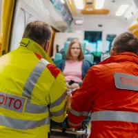 Kaksi ensihoitajaa auttavat potilaan ulos ambulanssista.