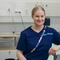 Fysioterapeutti istuu sairaalasängyn laidalla