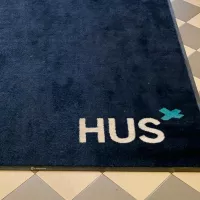 HUS-teksti matossa Kirurgisessa sairaalassa Helsingissä.