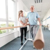 hoitaja tukee potilasta potilaan kävellessä tukipuilla
