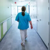 Hoitaja kävelee poispäin sairaalan käytävää pitkin.