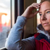 vaaleahiuksinen nainen katselee junan ikkunasta
