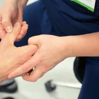 Fysioterapeutti tutkii potilaan kättä. 