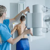röntgenhoitaja valmistautuu kuvaamaan selkää  