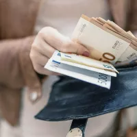 Nainen laittaa seteleitä lompakkoon.