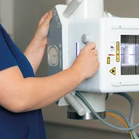 Tunnistamaton röntgenhoitaja työssään sinisessä työasussa.