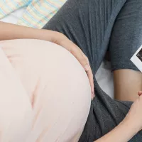 Raskaana oleva nainen katsoo kädessään olevaa ultraäänikuvaa sikiöstä.