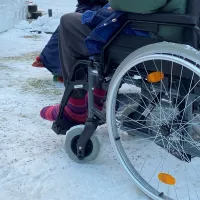 Vanhus on pyörätuolilla ulkoilemassa talvisessa kelissä.