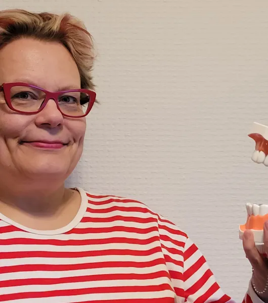 Nainen pitää hammashallia kädessään.