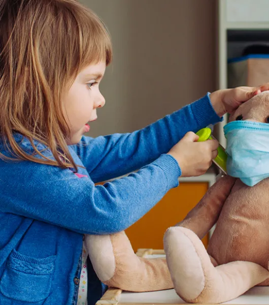 Pikkutyttö leikkii lääkäriä ja antaa rokotteen pehmolelu jänikselle.