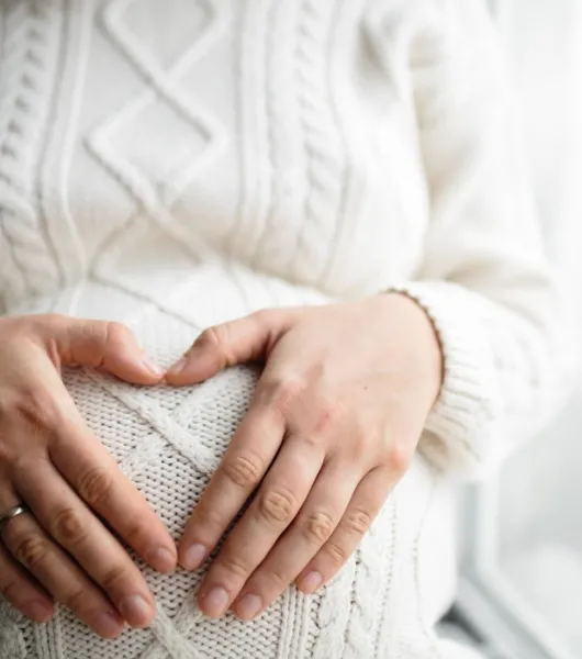 naisen raskausvatsa ja kädet sen päällä sydämen muodossa