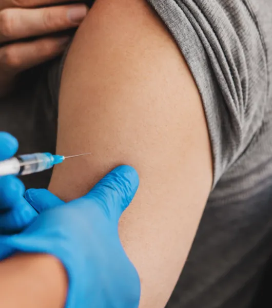 Hoitaja antaa henkilölle rokotteen käsivarteen.