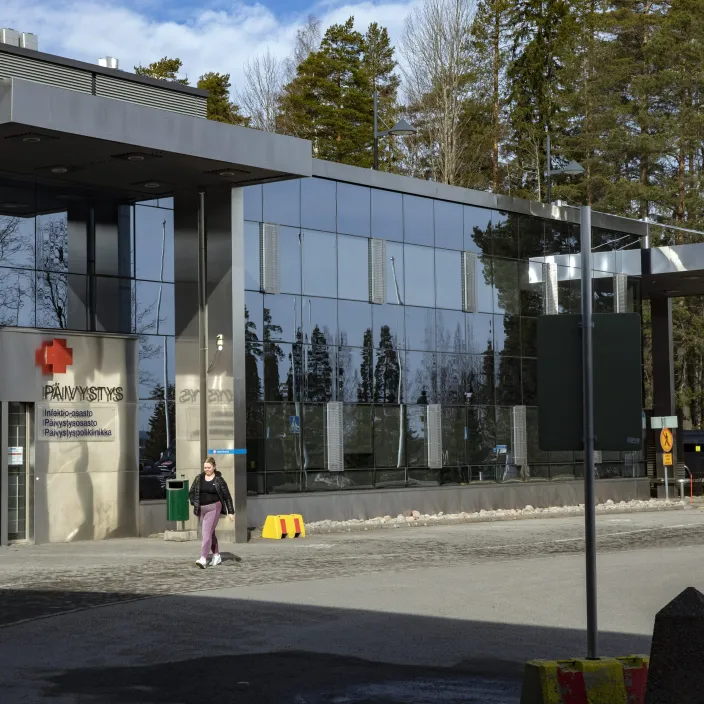 Sairaalan pihalla kävelee ihminen.