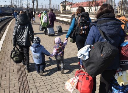 Ukrainalaisia pakolaisia rautatieasemalla raiteiden vieressä tavaroineen.