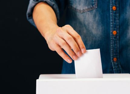 Ihminen sujauttaa äänestyslipuketta laatikkoon