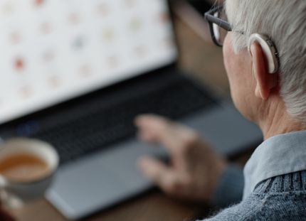 Tuoreen väitöstutkimuksen mukaan digipalvelujen onnistumista pitäisi mitata sillä, saako ihminen avun. Vanhus kuulokojeen kanssa käyttämässä tietokonetta.