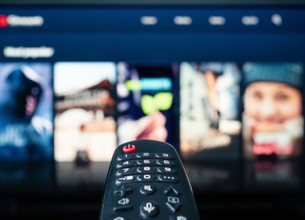 Kaukosäädin osoittaa televisioruudulla näkyvää suoratoistopalvelua.