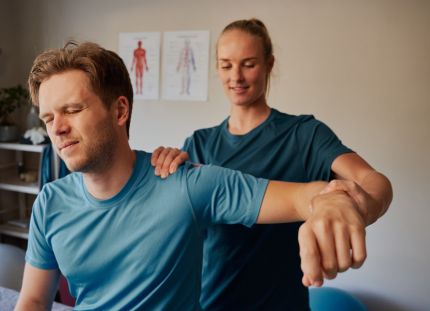 Fysioterapeutti venyttää ja tutkii potilaan käsivartta vastaanotolla.