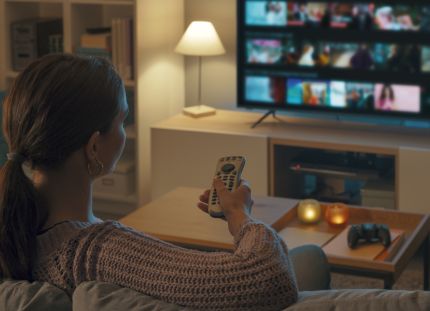 Millaisena hoitotyön ammattilainen näkyy elokuvissa – sankarina, sivuhahmona vai stereotyyppinä? Nainen katsoo elokuvavalikoimaa tv:n suoratoistopalvelusta.