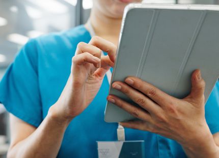 Hoitaja kirjaamassa tai katselemassa tietoja tabletilla.