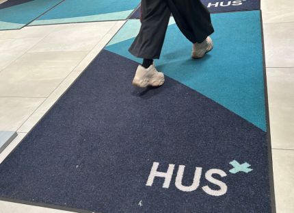 Alle 13-vuotiaiden lasten psykiatriseen hoitoon pääsee Husissa nopeasti. Nuori kävelee sairaalassa maton yli, jossa Husin logo.