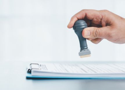 Käsi leimaamassa paperipinoa.