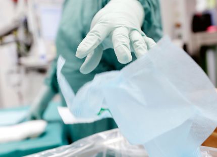 Suojavaatteisiin pukeutunut hoitaja laittaa kertakäyttöliinaa jätteisiin.