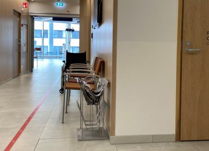 Sairaalan tyhjä käytävä. Seinustalla tuoleja. 
