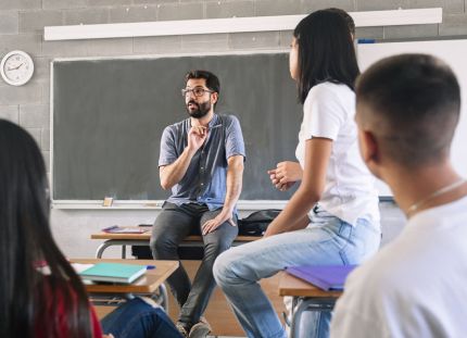 Innostunut miesopettaja puhuu ja oppilaat kuuntelevat kiinnostuneina.