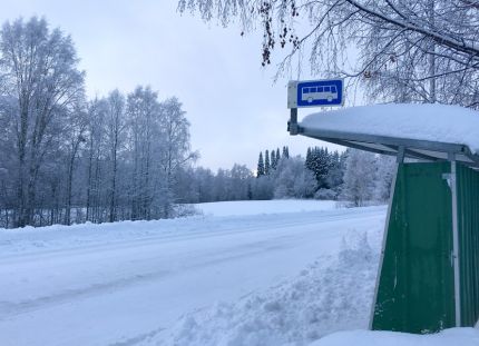 Linja-autopysäkki syrjäseudulla keskellä talvista lumimaisemaa.