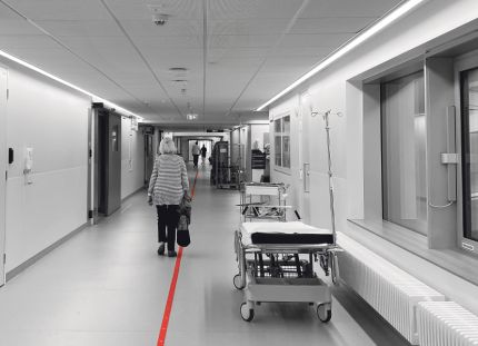 Vanus kävelee sairaalan pitkää käytävää poispäin kamerasta.
