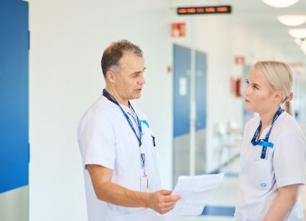 Keusote aloittaa uudet yt-neuvottelut. Kaksi hoitajaa keskustelemassa sairaalan käytävällä.